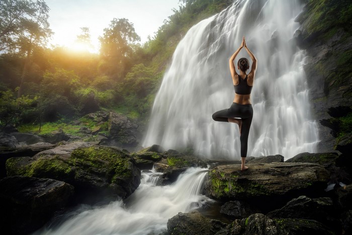Woman practicing yoga at a waterfall