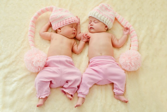 Two infants sleeping in winter hats