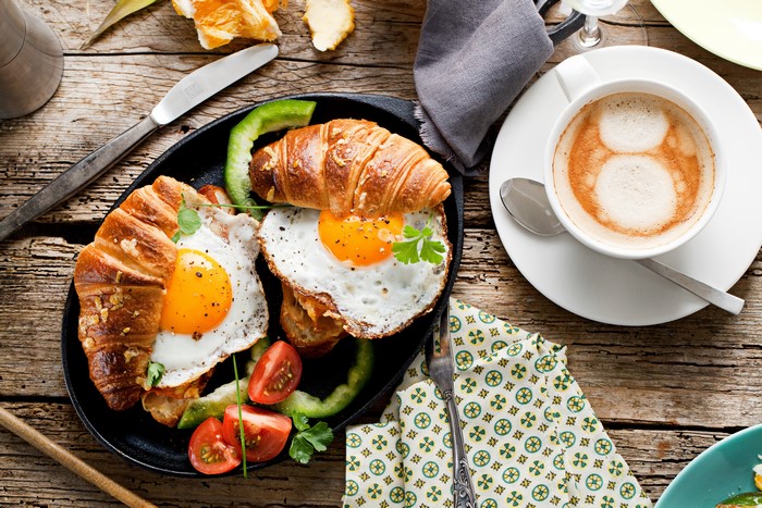 Breakfast with fried eggs, croissants, and coffee