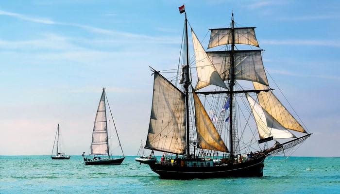 Sailing ships on the ocean under a blue sky