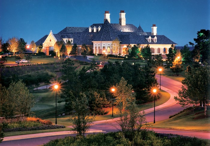 Large illuminated building at night with trees and street lights