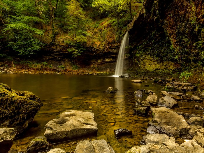 Waterfall cascading into a pool surrounded by rocks and trees
