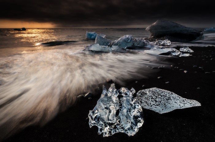 Icebergs on a black sand beach at sunset
