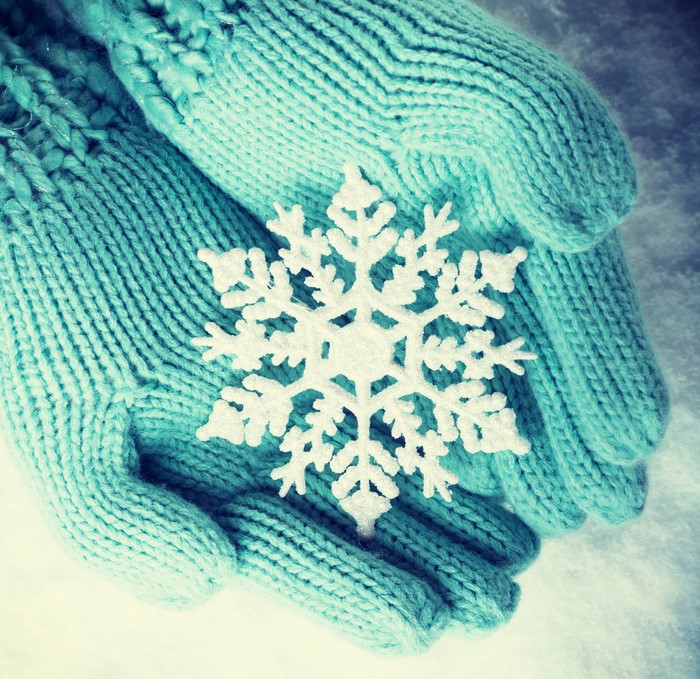 Hands in mittens holding a snowflake
