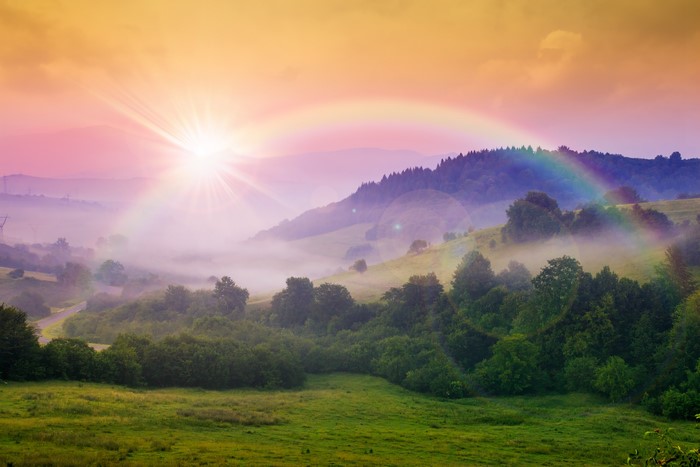 Sunrise with Rainbow over Misty Mountains and Forest