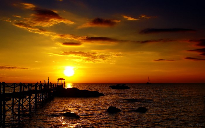 Sunset over the sea with a pier and boats