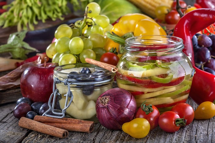 Assorted fruits and vegetables with jars of preserves