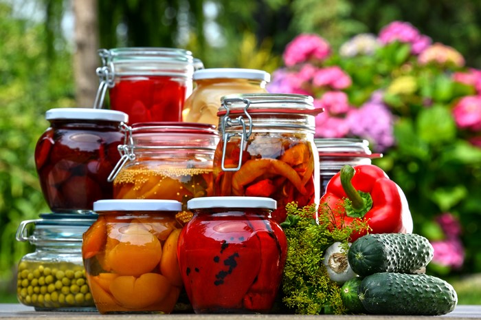 Jars of Preserved Fruits and Vegetables with Fresh Produce