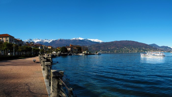 Baveno, Italy lakefront with snow-capped mountains and a ferry