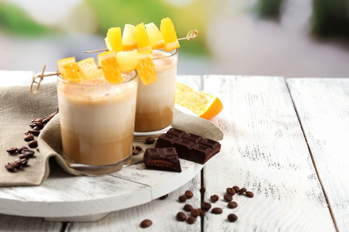 Two coffee drinks with orange garnish and chocolate