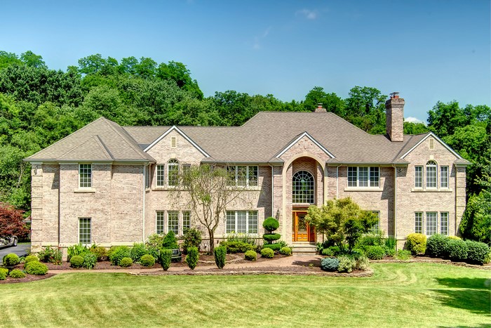 Large brick house with manicured lawn and trees