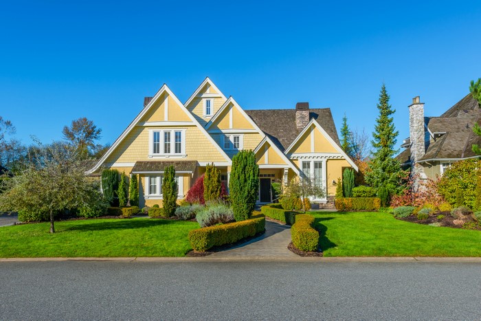 Yellow suburban house with manicured lawn and trees