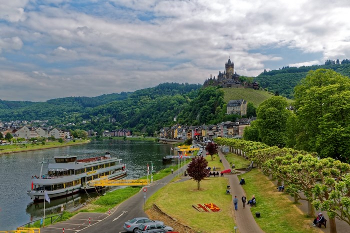 Cochem Castle overlooking a river with a cruise ship in Germany