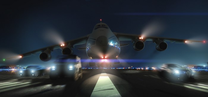 Airplane and cars on a runway at night