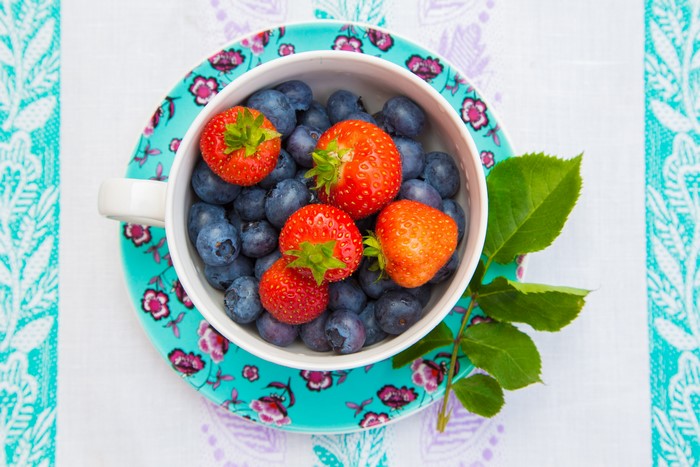 Strawberries and blueberries in a cup on a patterned plate