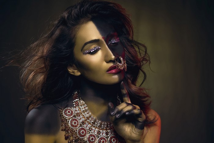 Woman with dramatic half-face makeup and jewelry