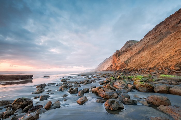 Rocky beach with cliffs and ocean at sunset