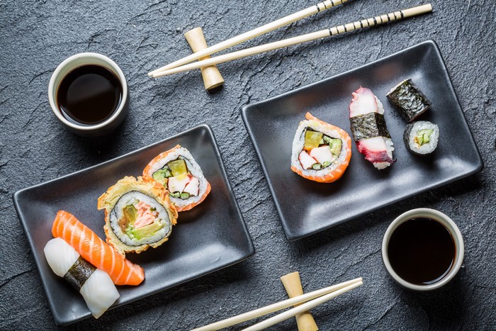 Sushi and soy sauce on a dark table with chopsticks