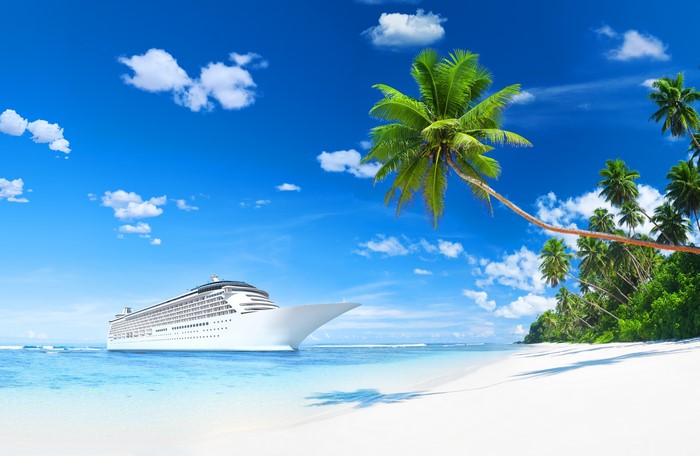 Cruise liner sailing near a tropical beach with palm trees