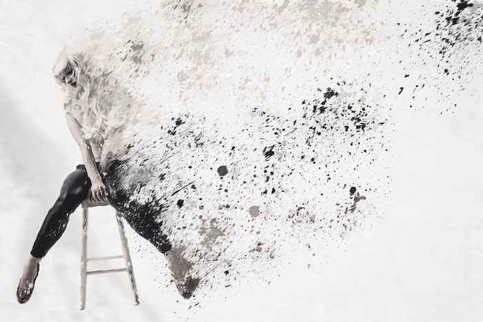 Woman dissolving into paint splatters on a stool