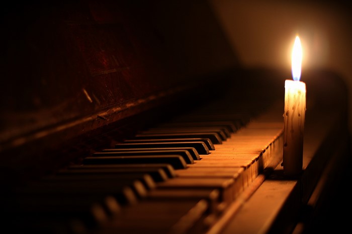 Candle burning on a piano keyboard