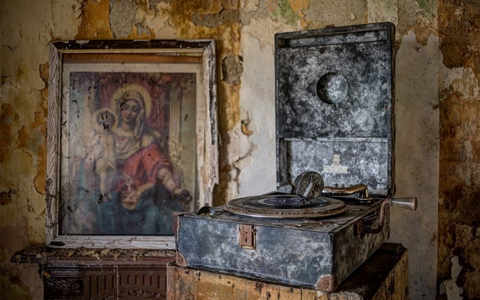 Antique gramophone and religious painting in abandoned room