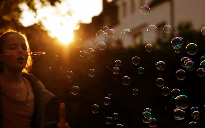 Girl blowing bubbles at sunset