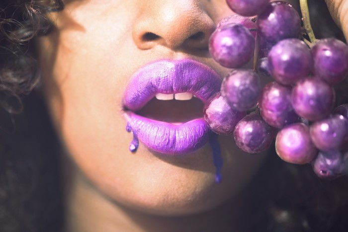 Woman with purple lips and grapes