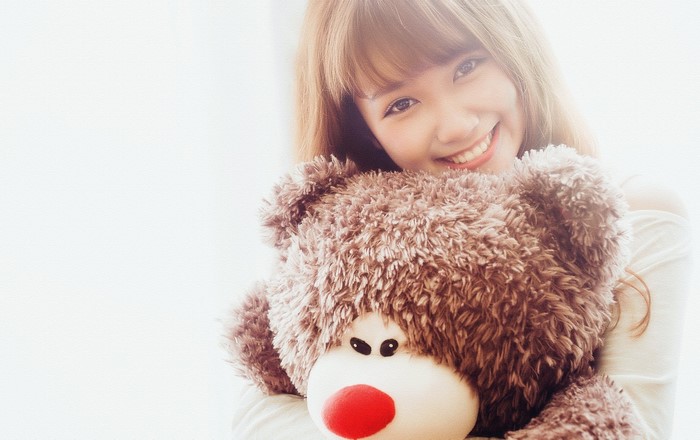 Young Asian woman hugging a large teddy bear