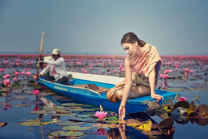 Woman in traditional dress in a boat with lotus flowers