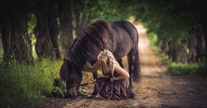 Blonde girl with horse on a dirt road