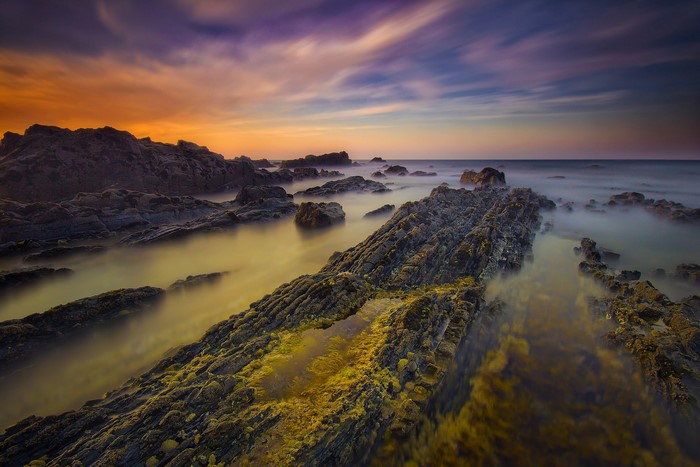 Rocky coastline at sunset with misty water