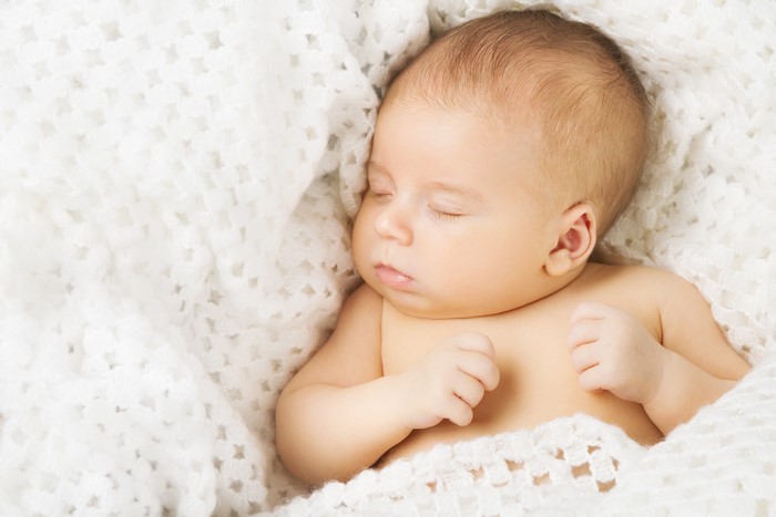 Infant sleeping on a white blanket