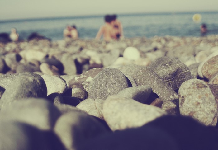 Pebble beach with people in the ocean