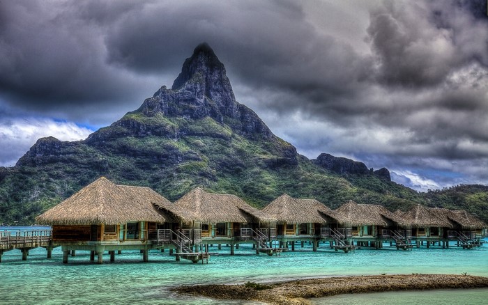 Overwater bungalows with a mountain backdrop