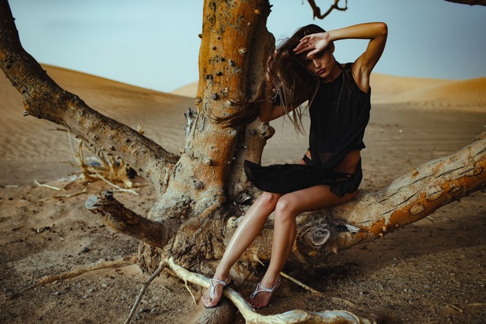 Woman sitting on a dead tree in the desert