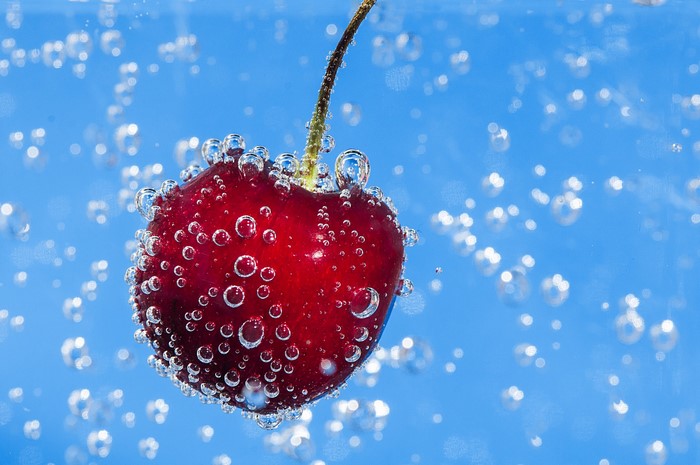 Cherry submerged in sparkling water with bubbles