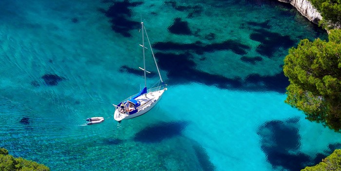 Sailboat and dinghy in a turquoise cove