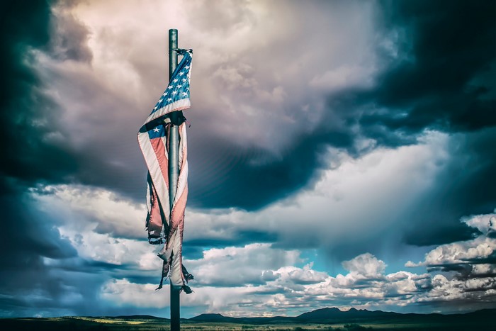 Tattered American Flag Against Stormy Sky