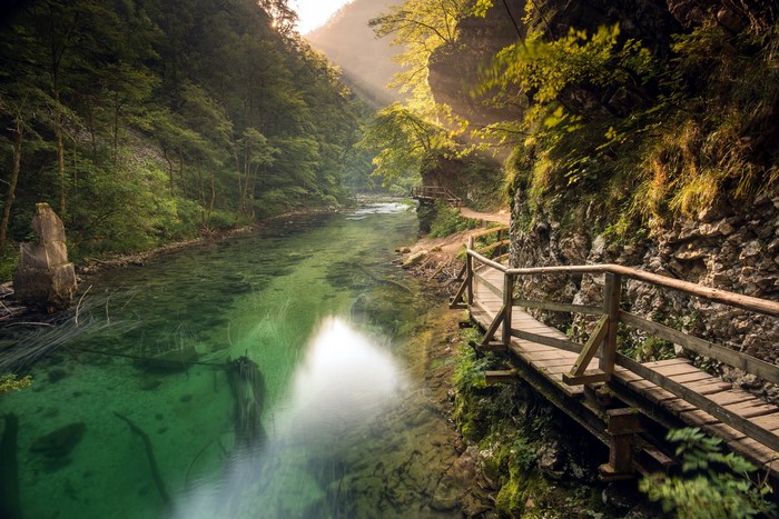 Wooden walkway along a clear green river in Slovenia