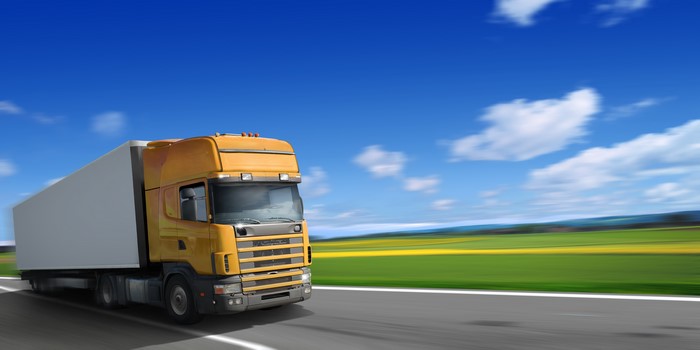 Yellow truck with white trailer on a road