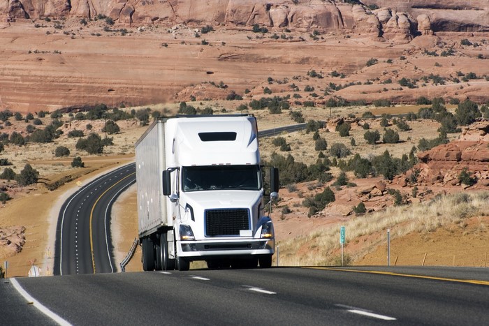 White semi-truck driving on a desert highway