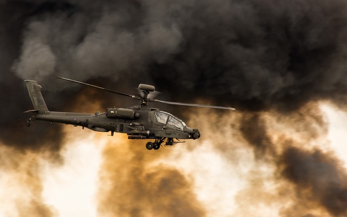 AH-64 Apache helicopter flying through smoke