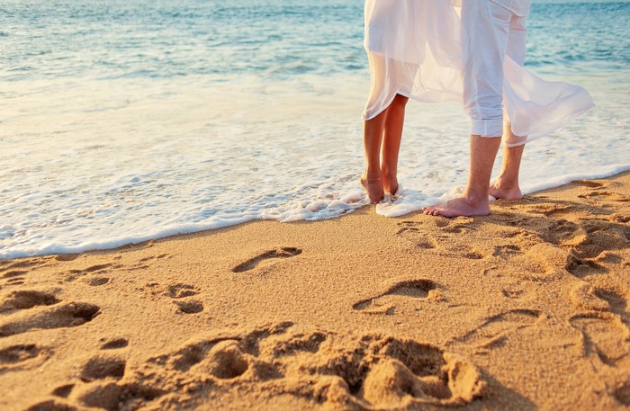 Couple's Legs on a Sandy Beach with Footprints
