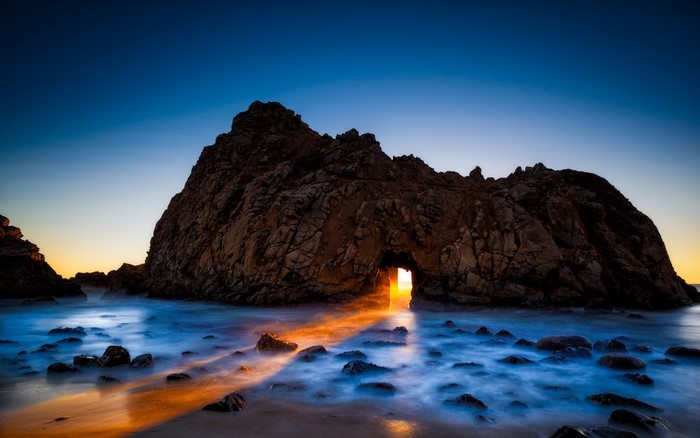 Sunset through rock arch at Pfeiffer Beach, Big Sur, California