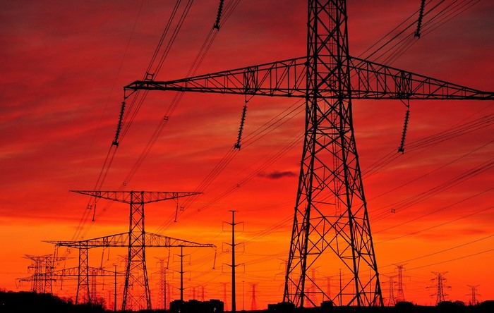 Power lines silhouetted against a fiery sunset sky