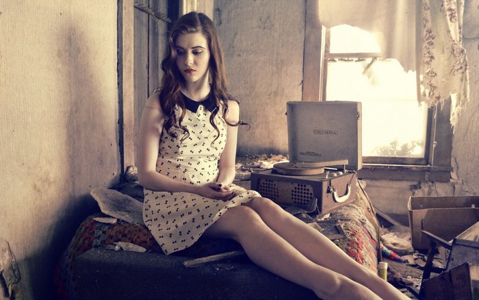 Woman sitting in a dilapidated room with a record player