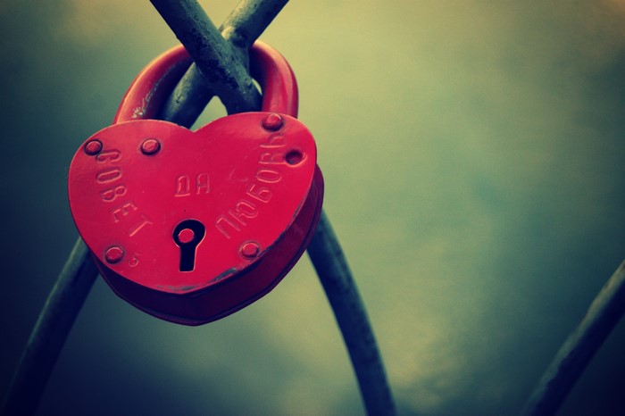 Red heart-shaped padlock on metal bars