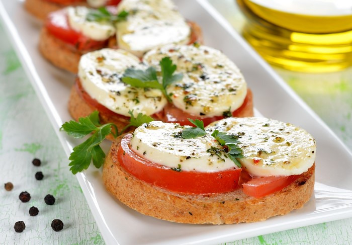 Bruschetta with tomatoes and cheese on a white plate