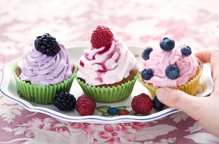 Three berry cupcakes on a decorative plate